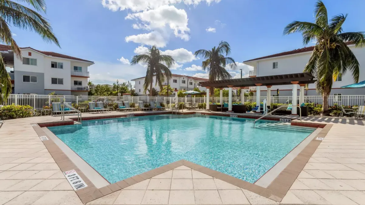 White apartment building with pool in the foreground.