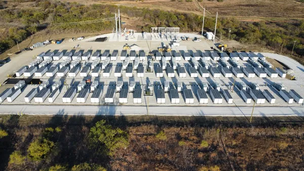 Rows of large containers with electric power lines in the background.