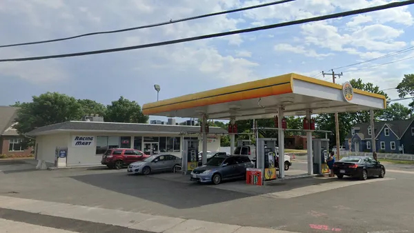 A photo of the exterior of a gas station and convenience store. A sign on the wall of the store says Racing Mart.