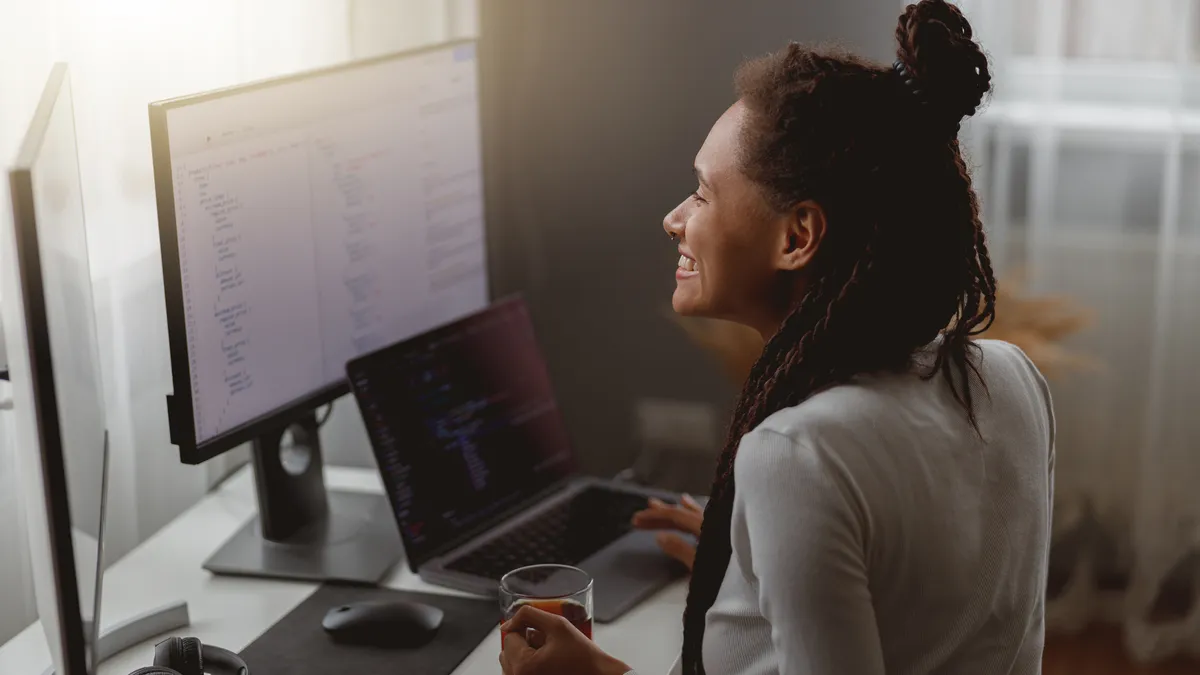 Close up of happy IT worker coding on computer at home looking at monitor