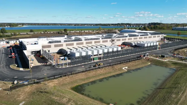 Aerial view of a large building with a large retention pond in front of it.