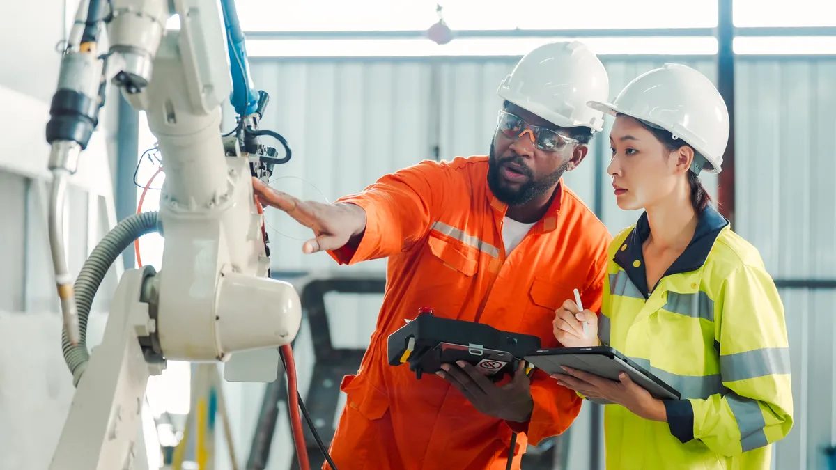 Two people discuss and train in a robotics plant.