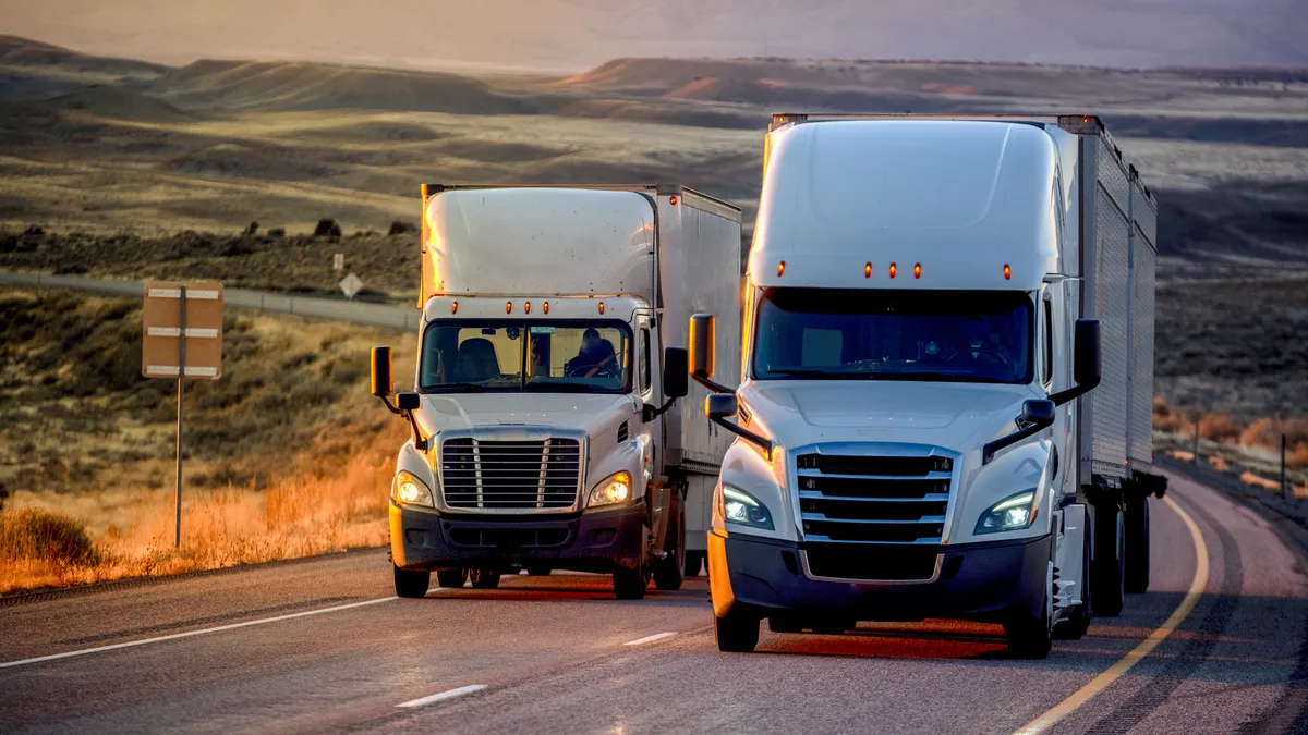 Trucks on a highway with plateaus and mountains in the background.