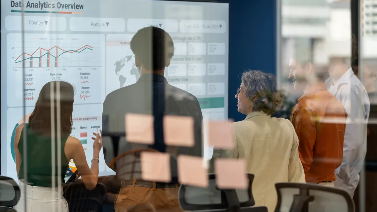 Diverse business development team brainstorming new products and services using a digital display during a business meeting.