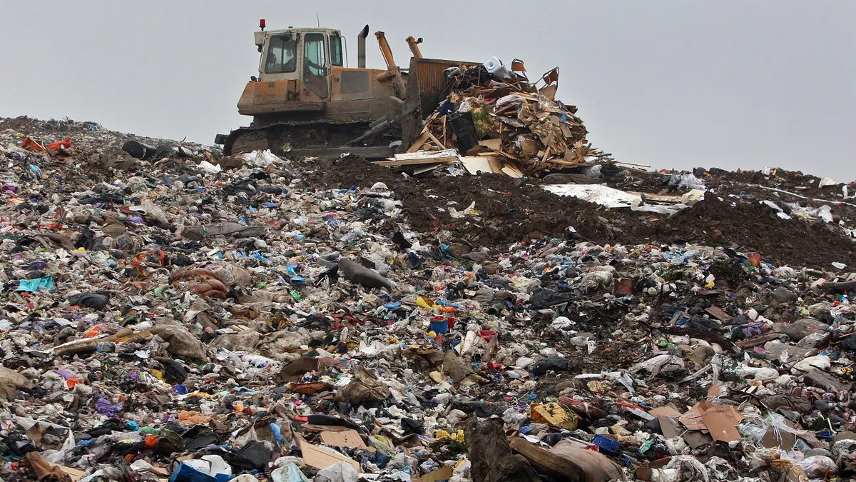 A bulldozer moves piles of trash at a landfill