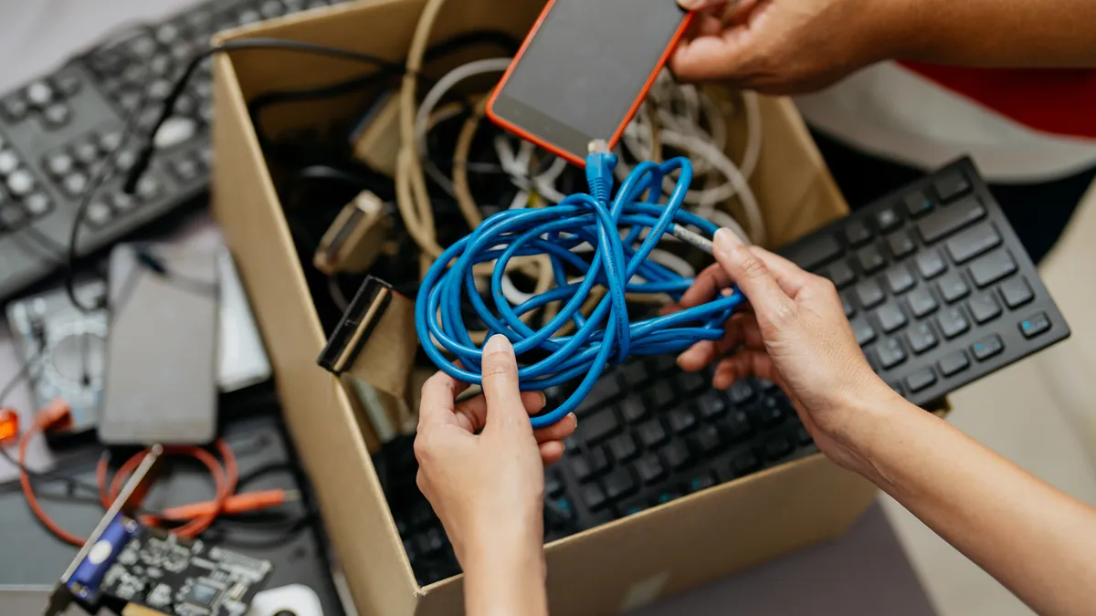 A box of e-waste including an old keyboard and cords