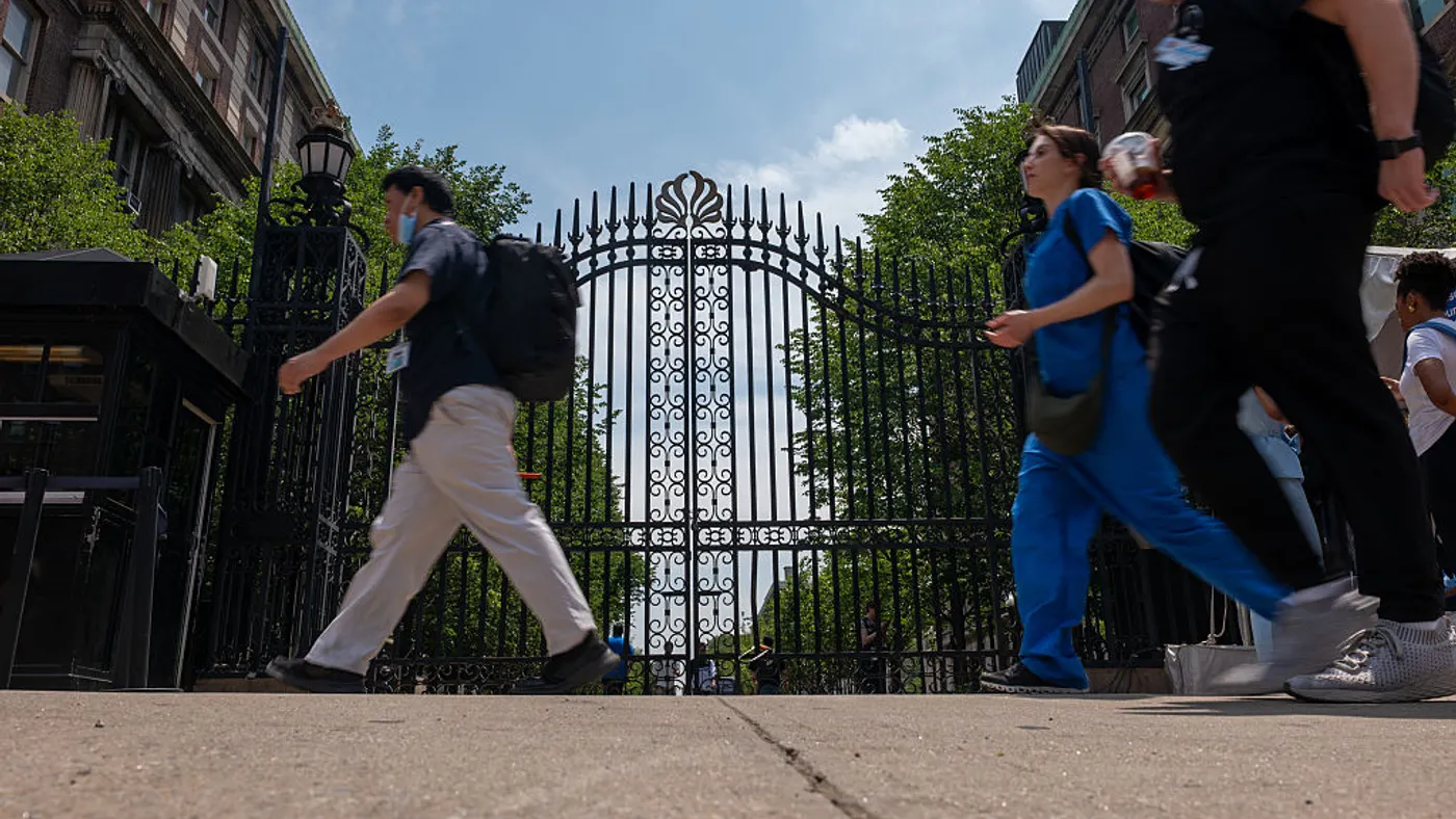 A few pedestrians walk by Columbia University's gates.