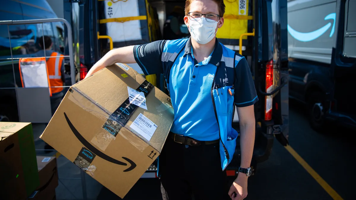 A delivery person holds an Amazon box.