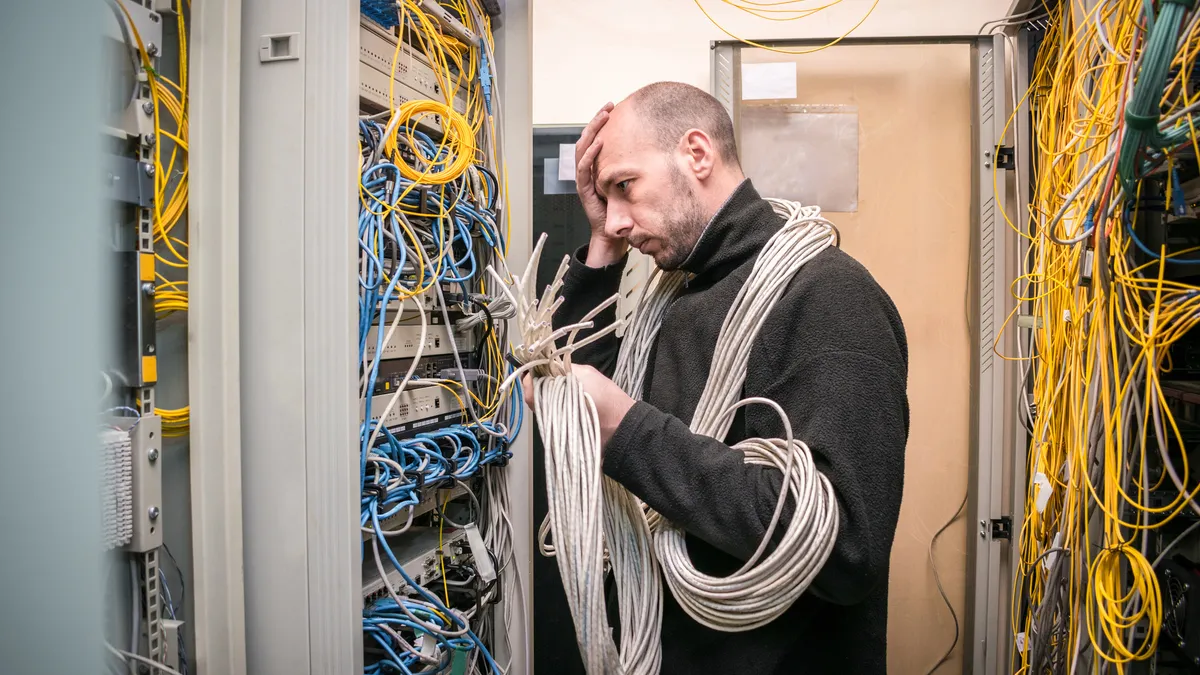 A man with many cables works in the server room of the data center.