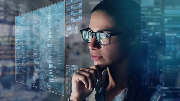 woman with glasses looking at a screen with data points