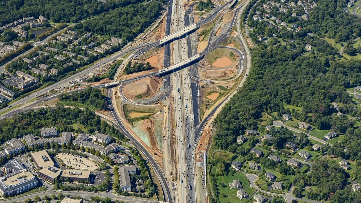 An aerial image of a set of large highways that overlap and loop around each other, surrounded by trees.