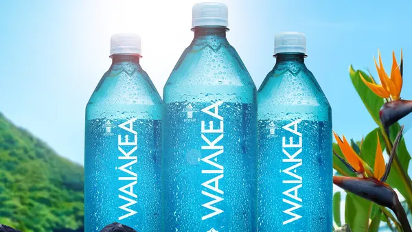 Three bottles of Waiakea bottled water are displayed against a tropical background.