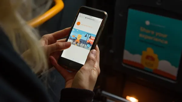 A woman looks down at the Headspace app on her phone.