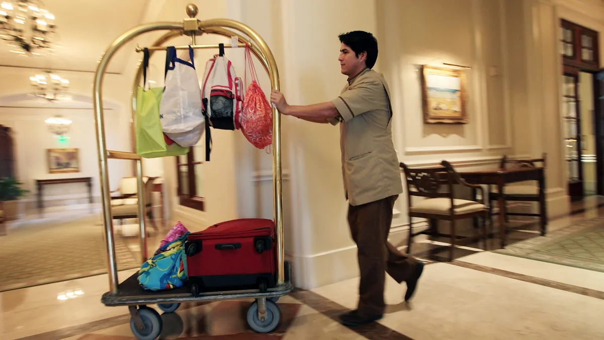 A hotel staffer pushes a luggage cart.