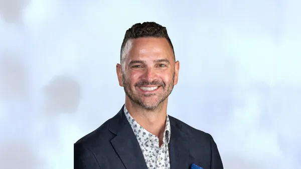 A head and shoulders photo of a person against a gray and white background.