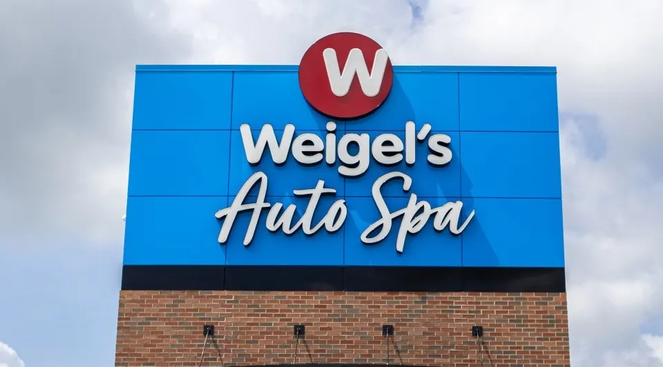 A photo of a sign, in blue and white. The sign says "Weigel's auto spa."
