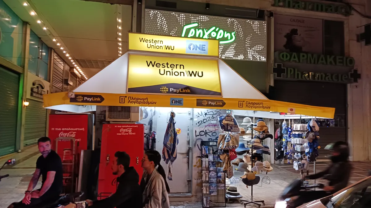 A Western Union sign light up in a busy Athens street.