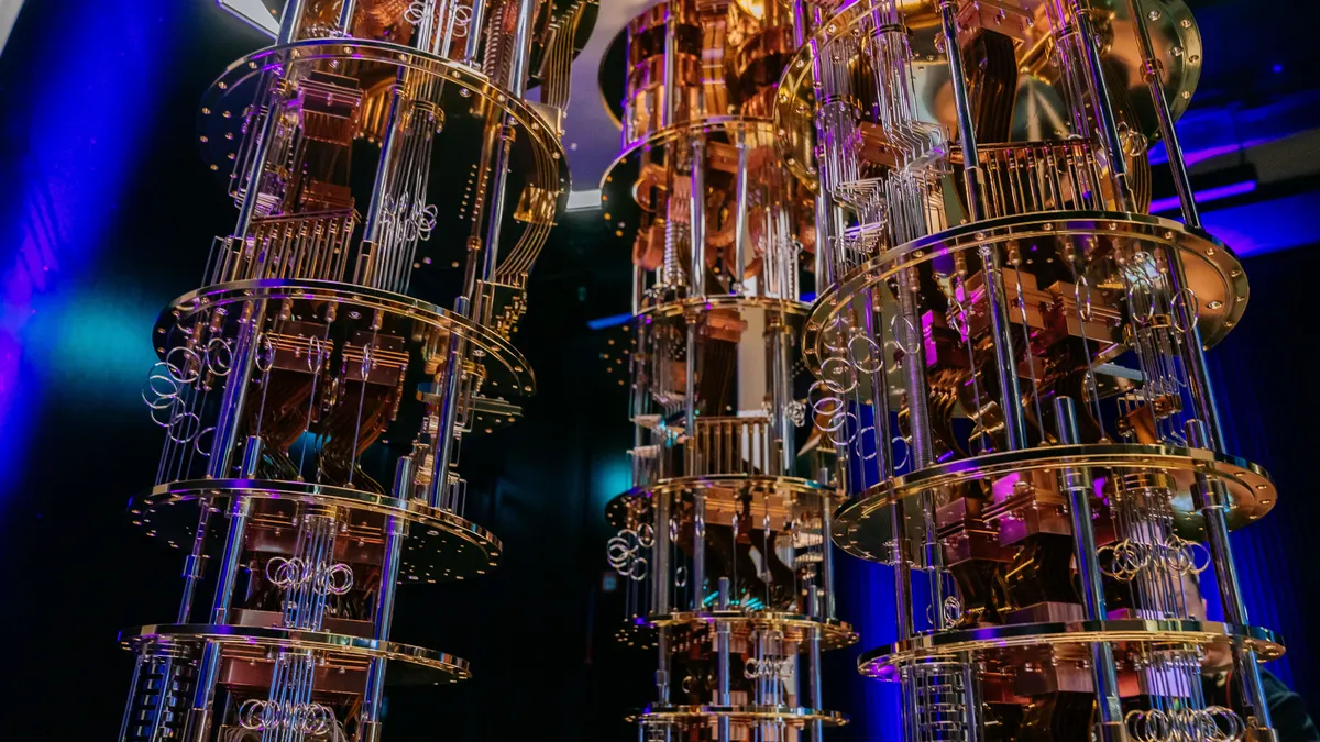Three orange-and-black chandelier-like objects are seen against a black and blue background