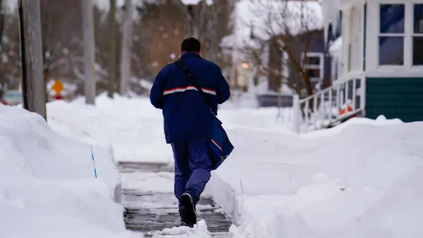 A person walks on a sidewalk in a snow-filled neighborhood.