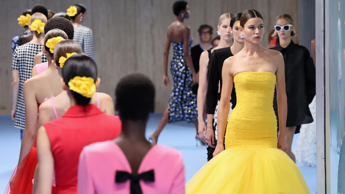 Models in colorful gowns walk the runway.