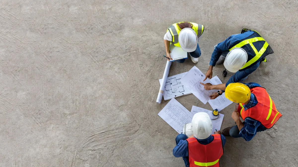 An aerial view of a group of construction workers looking at plans.