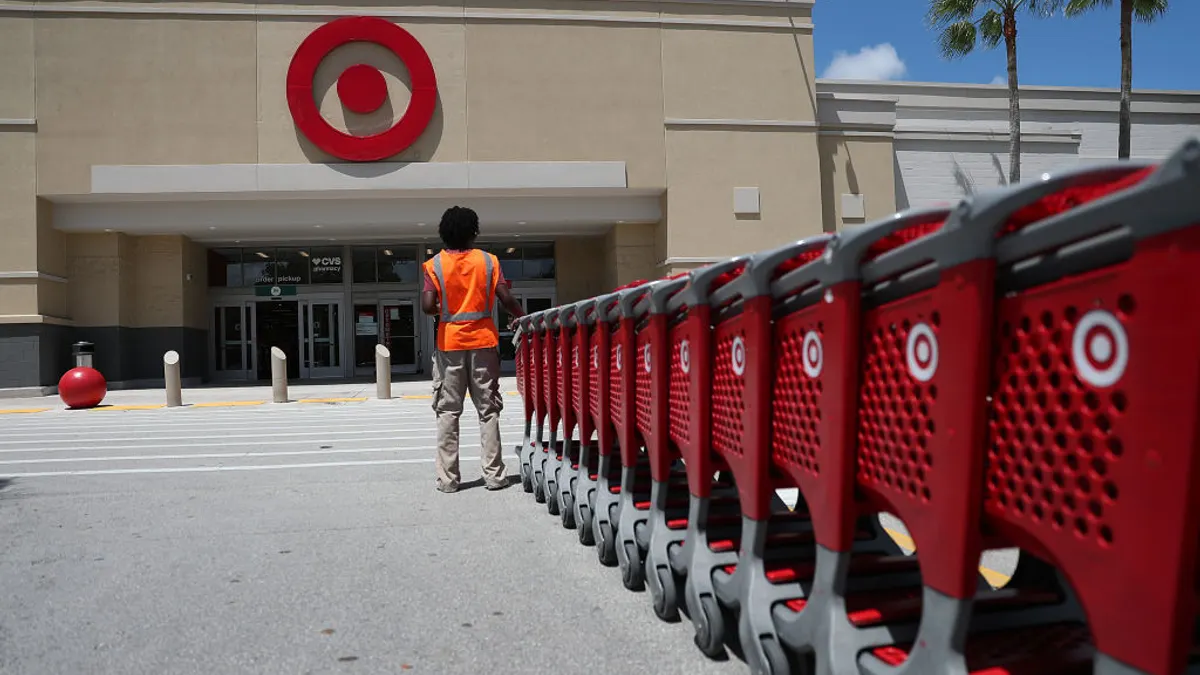 A Target store employee collects shopping carts in a parking lot.