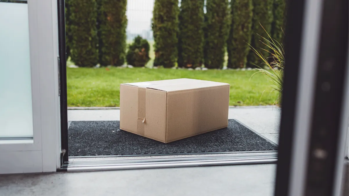 A cardboard box on a mat, located at the entrance in front of a door.