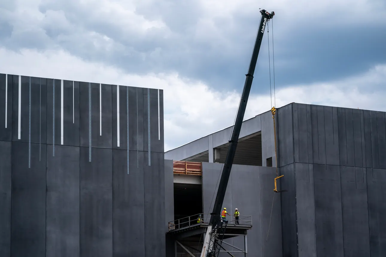 People in hard hats and safety gear work alongside a large crane to build a data center in Ashburn, Virginia.