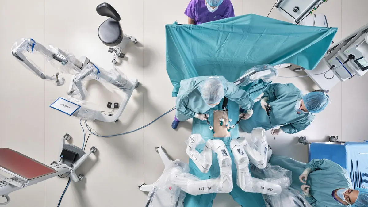 An aerial view of four clinicians and Distalmotion's Dexter surgical robot.