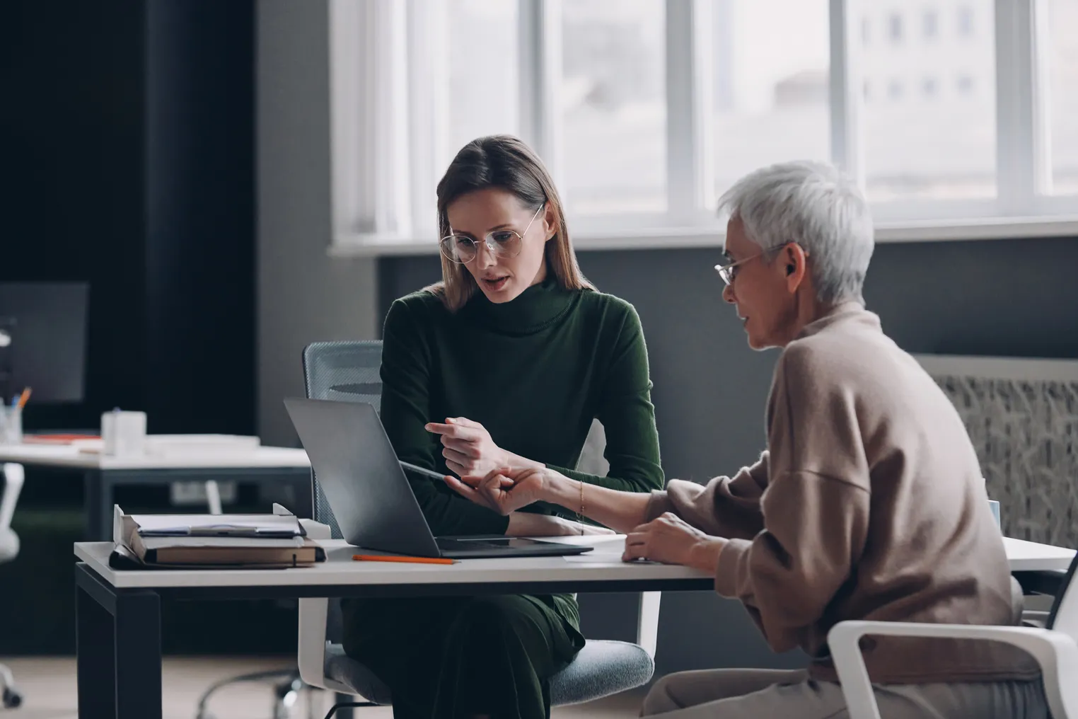 an older worker speaks with a younger worker during a meeting