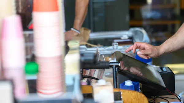 Coffee shop business owner standing at the cashier while working