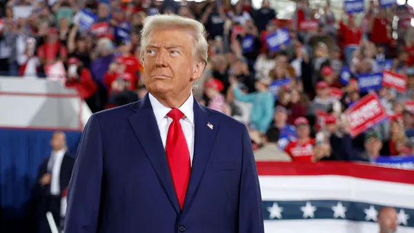 Donald Trump stands against a backdrop of supporters.