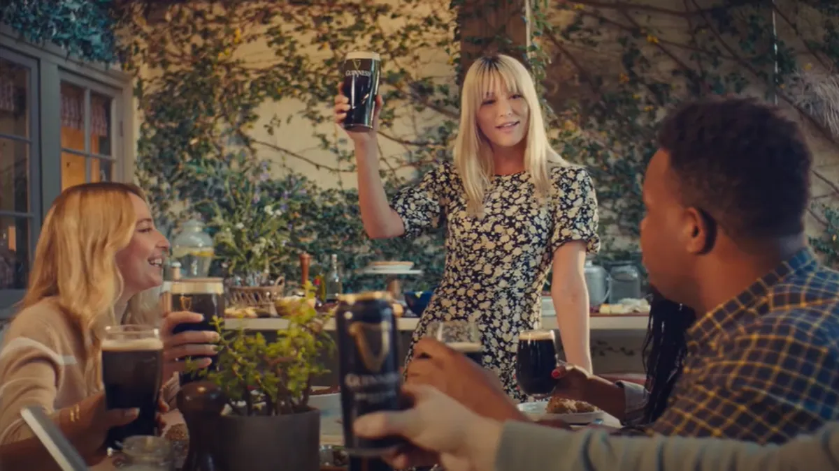 A group of friends sit around drinking Guinness.