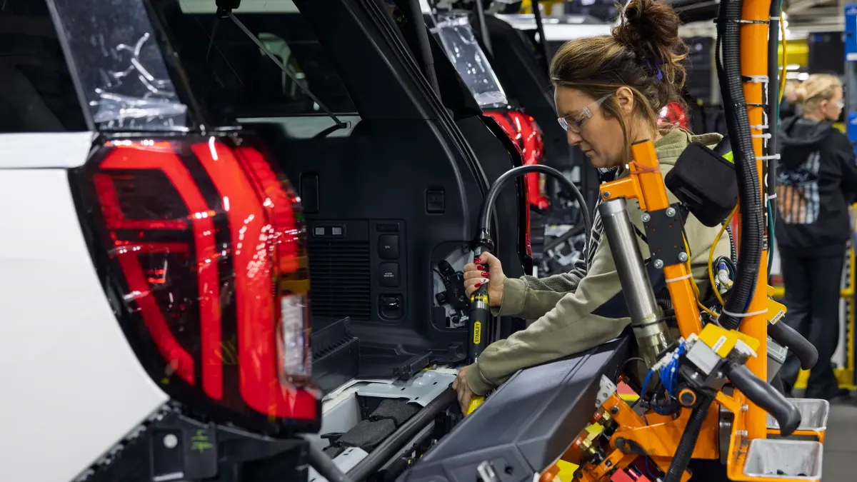 A Ford worker installing parts on a white Ford Expedition SUV at the automaker's Kentucky Truck Plant.