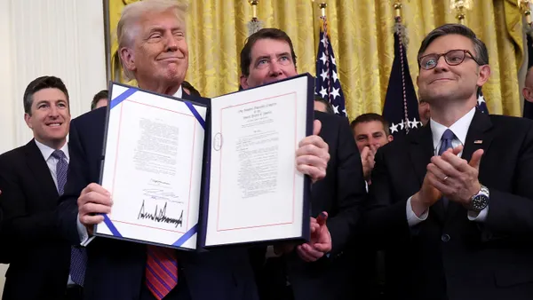 President Trump holds up document with House Speaker Johnson and others behind him.