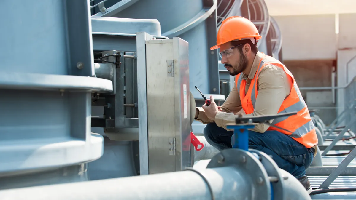 Engineer in protective gear inspecting cooling tower