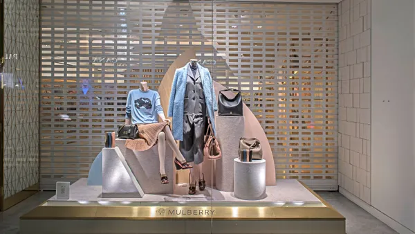 Clothing and handbags are displayed in a store window.