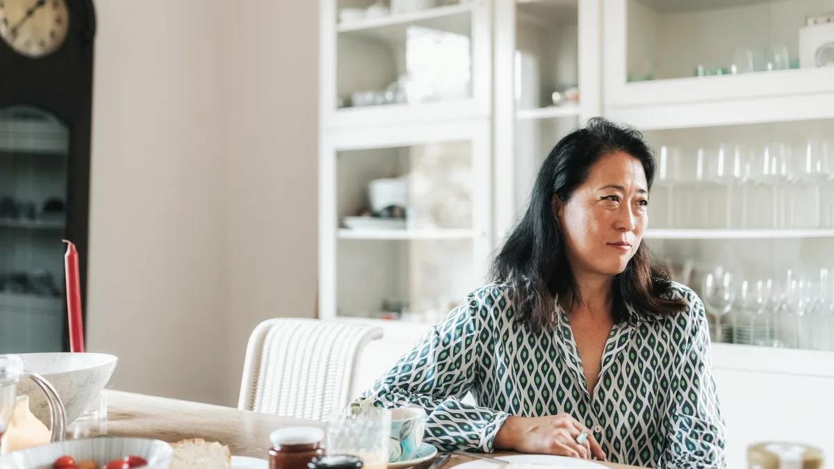 Asian woman sitting at a table and talking to someone