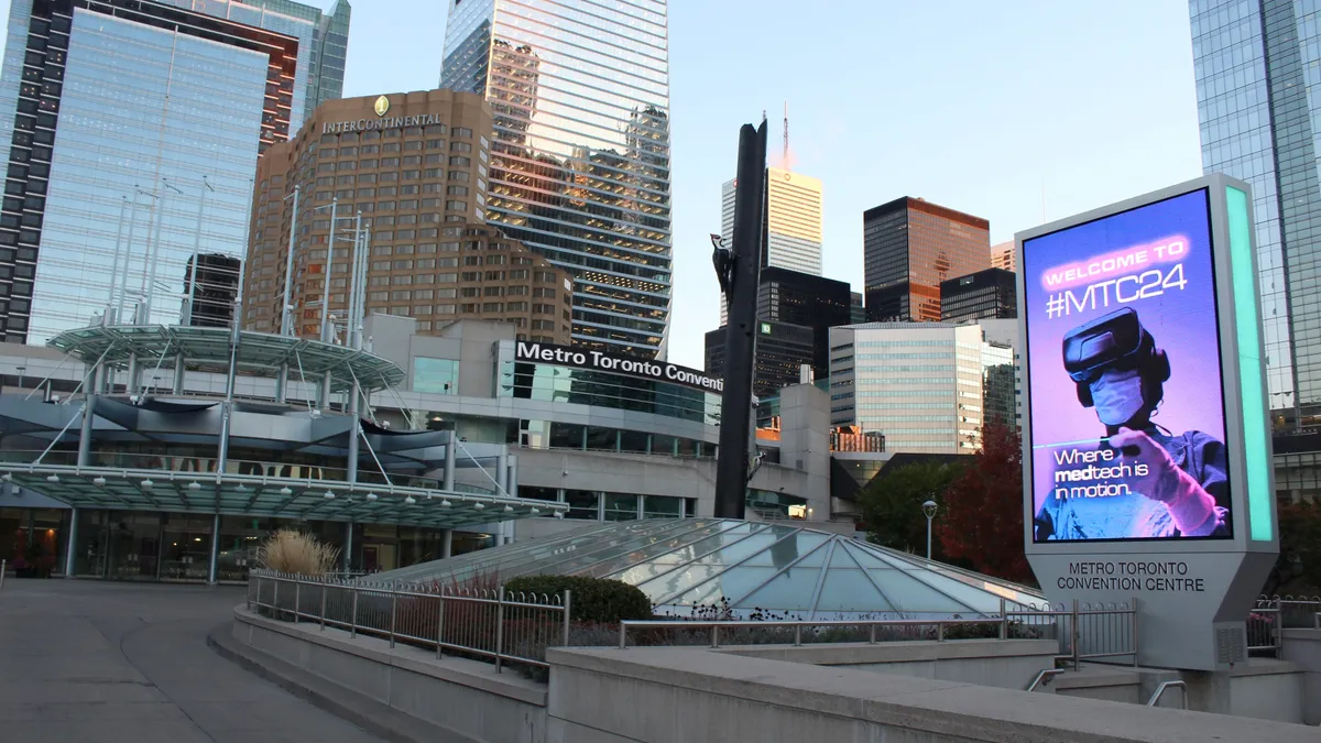 An exterior of a building with a sign that says "Welcome to #MTC24" in front of a downtown skyline.