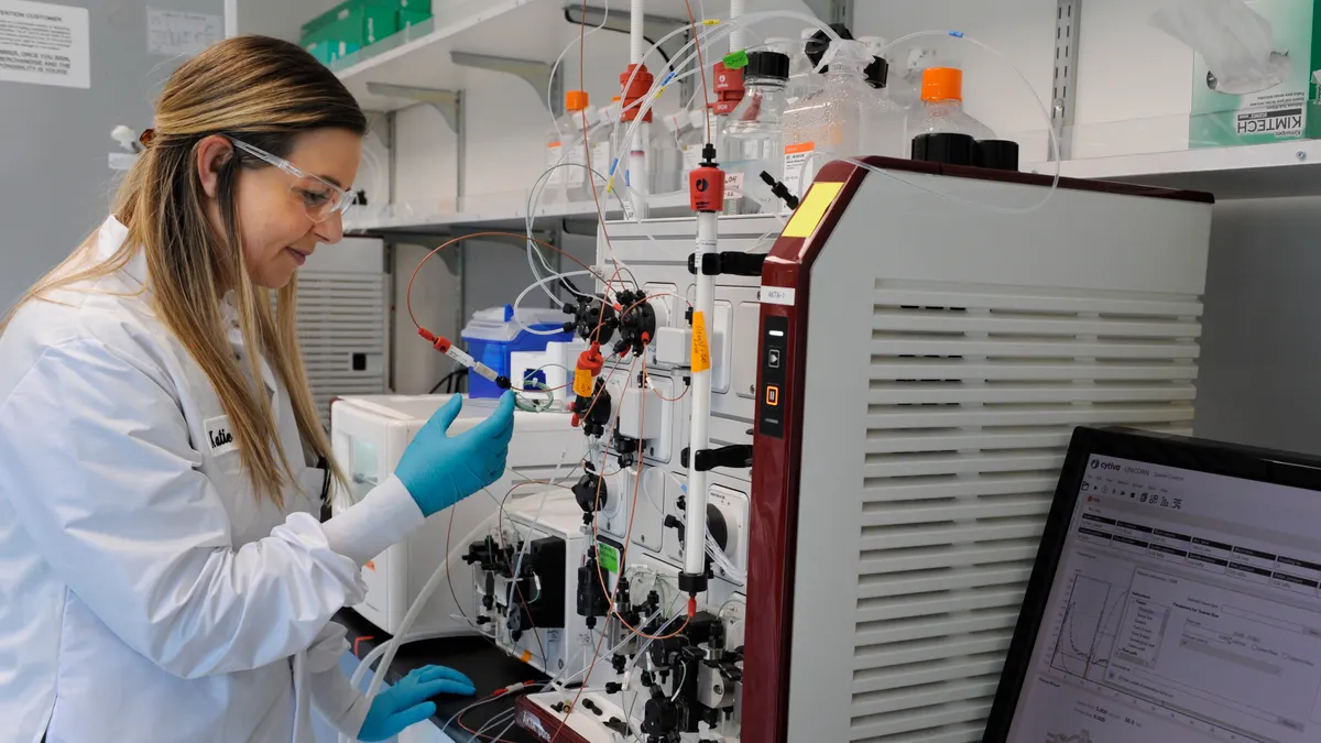 A researcher, wearing a white coat, works in a lab.