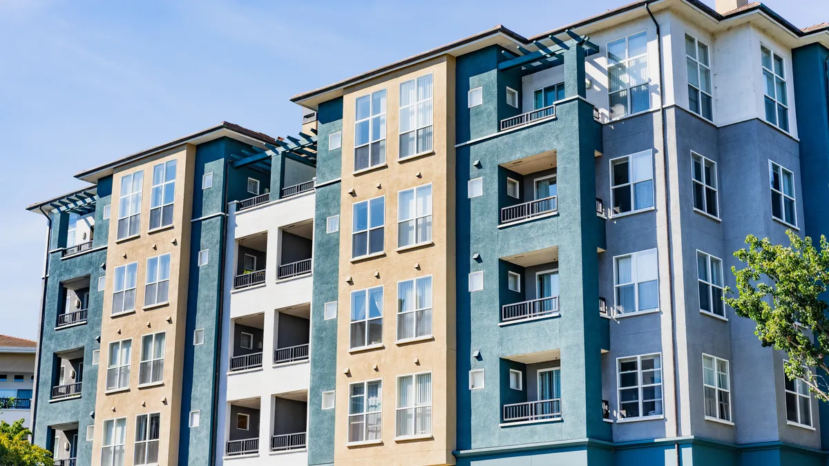 A modern, mid-rise apartment building with a blue and yellow paneled exterior.