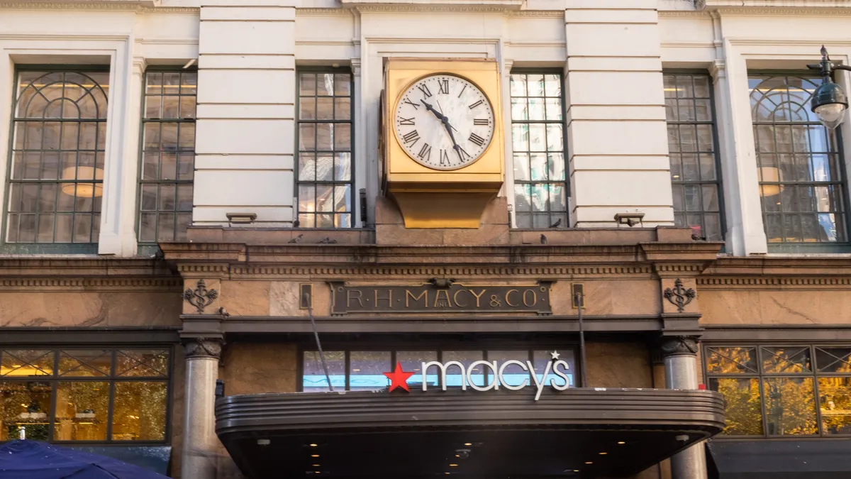 At the main entrance to Macy's in New York, a gilded clock and the original "R.H. Macy & Co." sign sit above the modern logo.