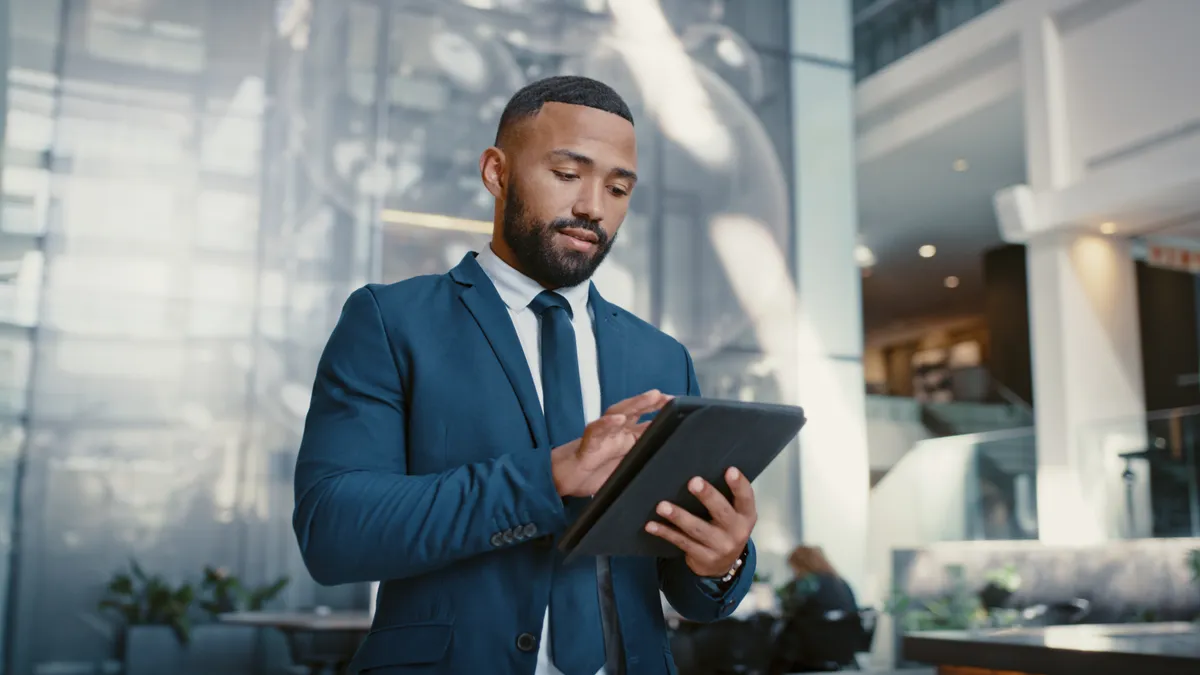 A man on a digital tablet for booking, planning and accommodation management while working at hotel front desk