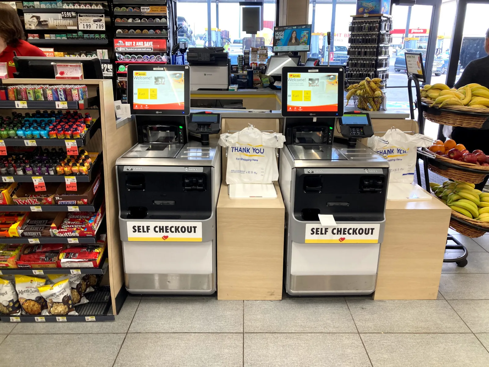 A photo of self checkout kiosks inside a convenience store. Each machine says &quot;self checkout.&quot;