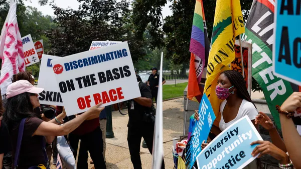 Protesters meet across a barrier line with differing signs.