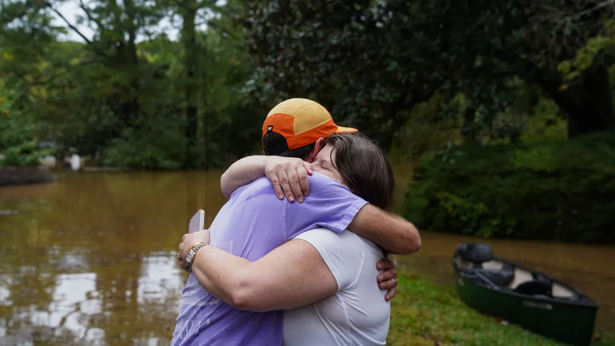 Two people hug in the midst of flooding