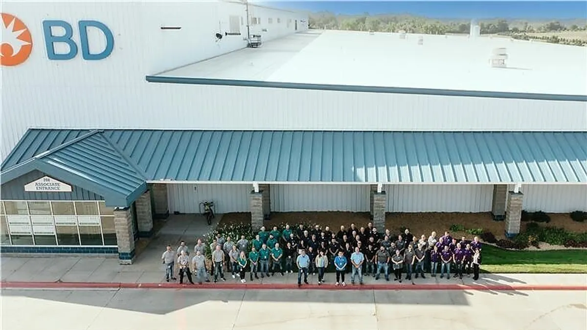 A large group of employees stand outside a facility.