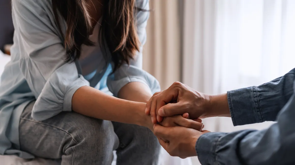 Man comforting woman holding hands