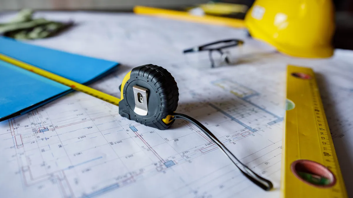 A tape measure and level sit on site plans.