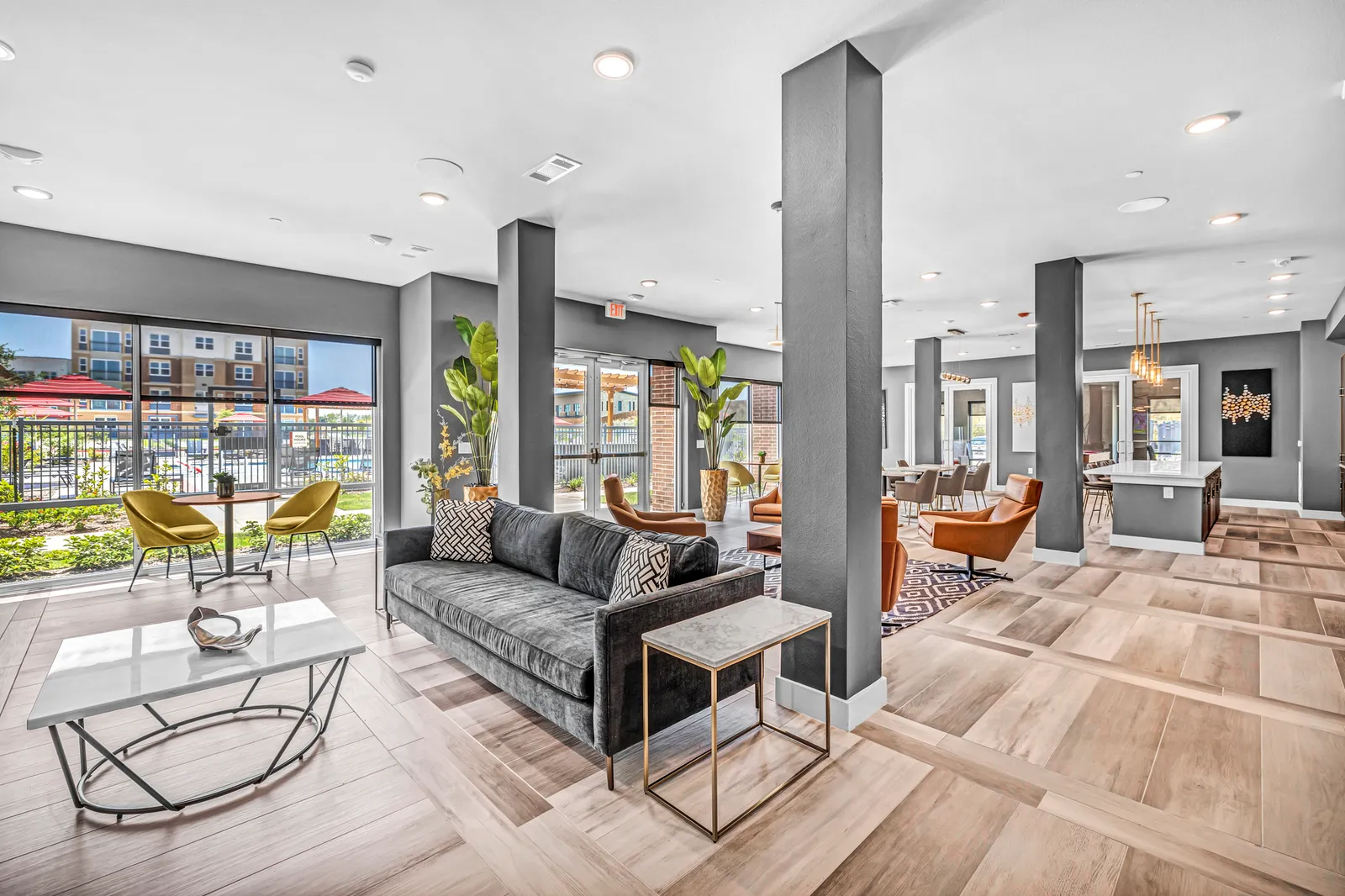 A large room with a wood floor, couches, tables and chairs.